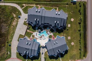 Um complexo residencial moderno com várias casas, uma piscina central e um gramado bem cuidado.