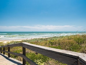 A wooden boardwalk leading to a beach with ocean views.