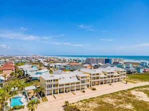 A coastal residential area with beachfront properties, a swimming pool, and a clear view of the ocean. - 3 Sheets To the Zin by Silver Sands Vacation Rentals (Port Aransas)