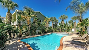 Une piscine entourée de palmiers et de chaises longues.