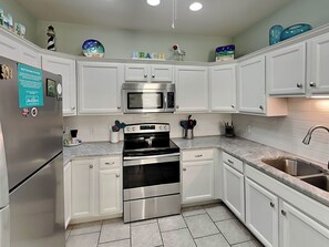 A modern kitchen with white cabinets, stainless steel appliances, and a tiled backsplash.