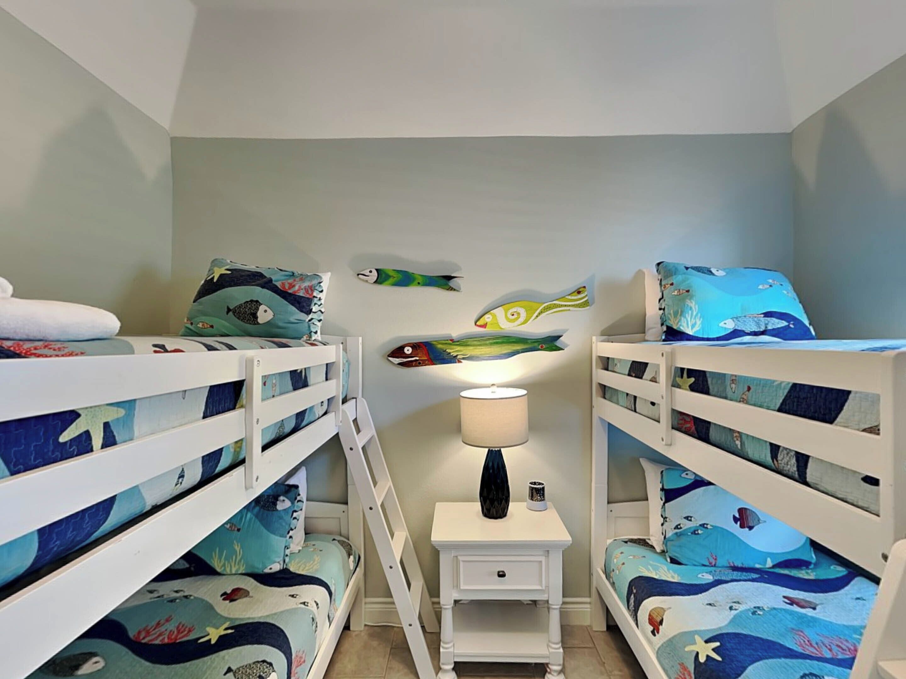Een kinderkamer met stapelbedden, een nachtkastje en decoraties aan de muur.