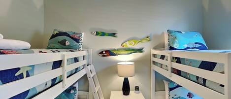 Een kinderkamer met stapelbedden, een nachtkastje en decoraties aan de muur.