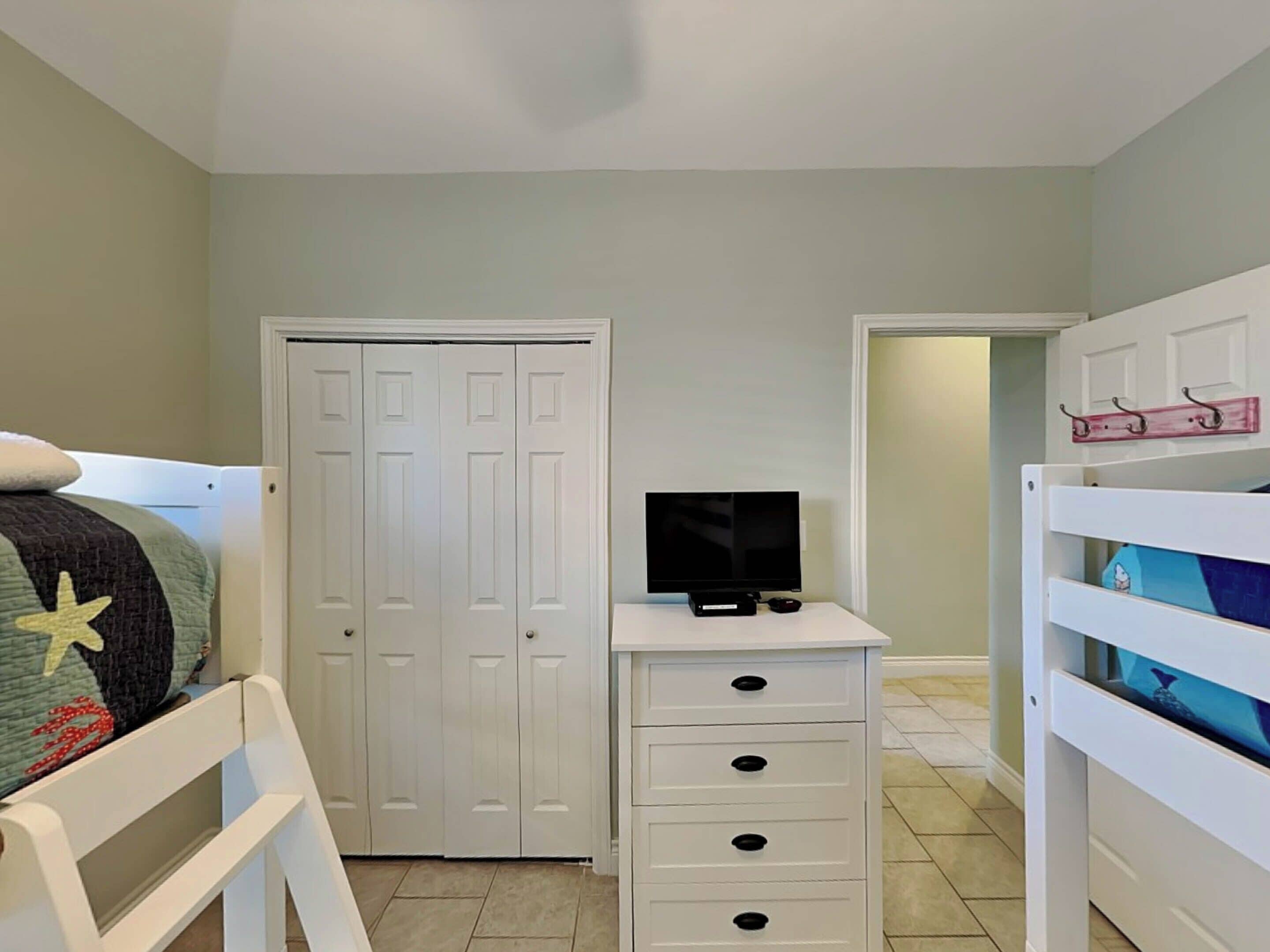 A bedroom with a bed, a wardrobe, a TV on a stand, and a bunk bed.