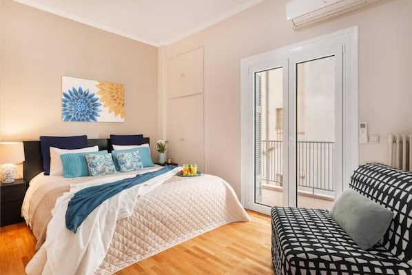 Une chambre à coucher comprenant un lit, une table de chevet, une commode, une fenêtre et une porte.