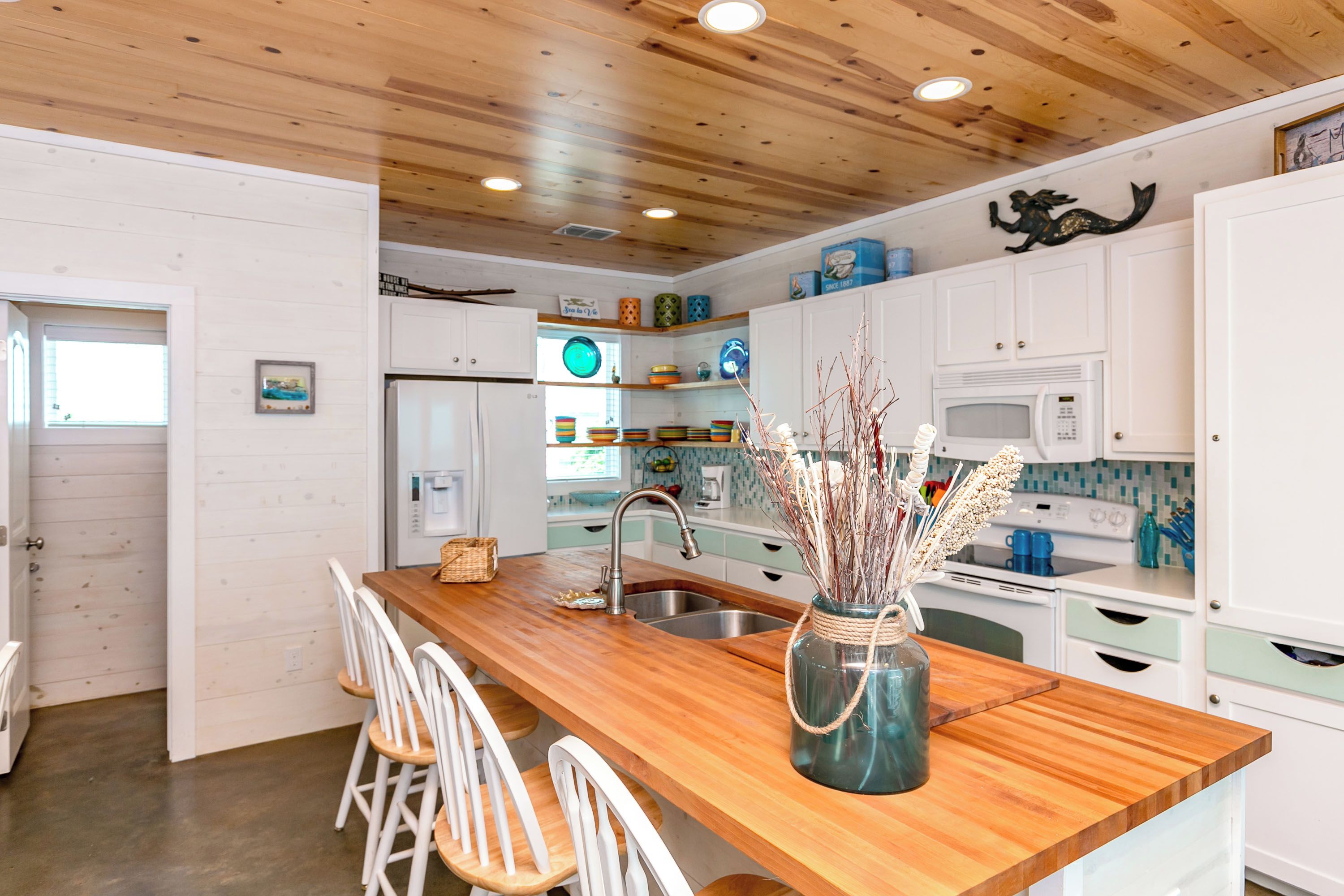 A modern kitchen with wooden countertops, white cabinets, and a central island with bar stools.