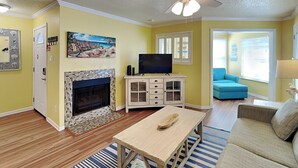 Un salon avec une cheminée, un téléviseur et un canapé bleu.