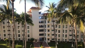 A multi-story hotel with a central courtyard, surrounded by palm trees and a red pathway. - Costa Vallarta by TRVL2HM (Nuevo Nayarit)