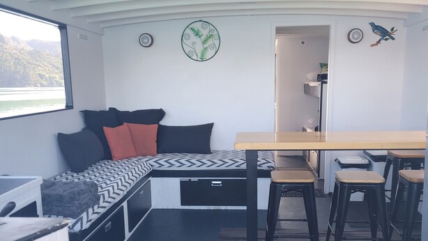 Een compacte, moderne kamer met een bed, een klein bureau en een raam met uitzicht op een fraai landschap.