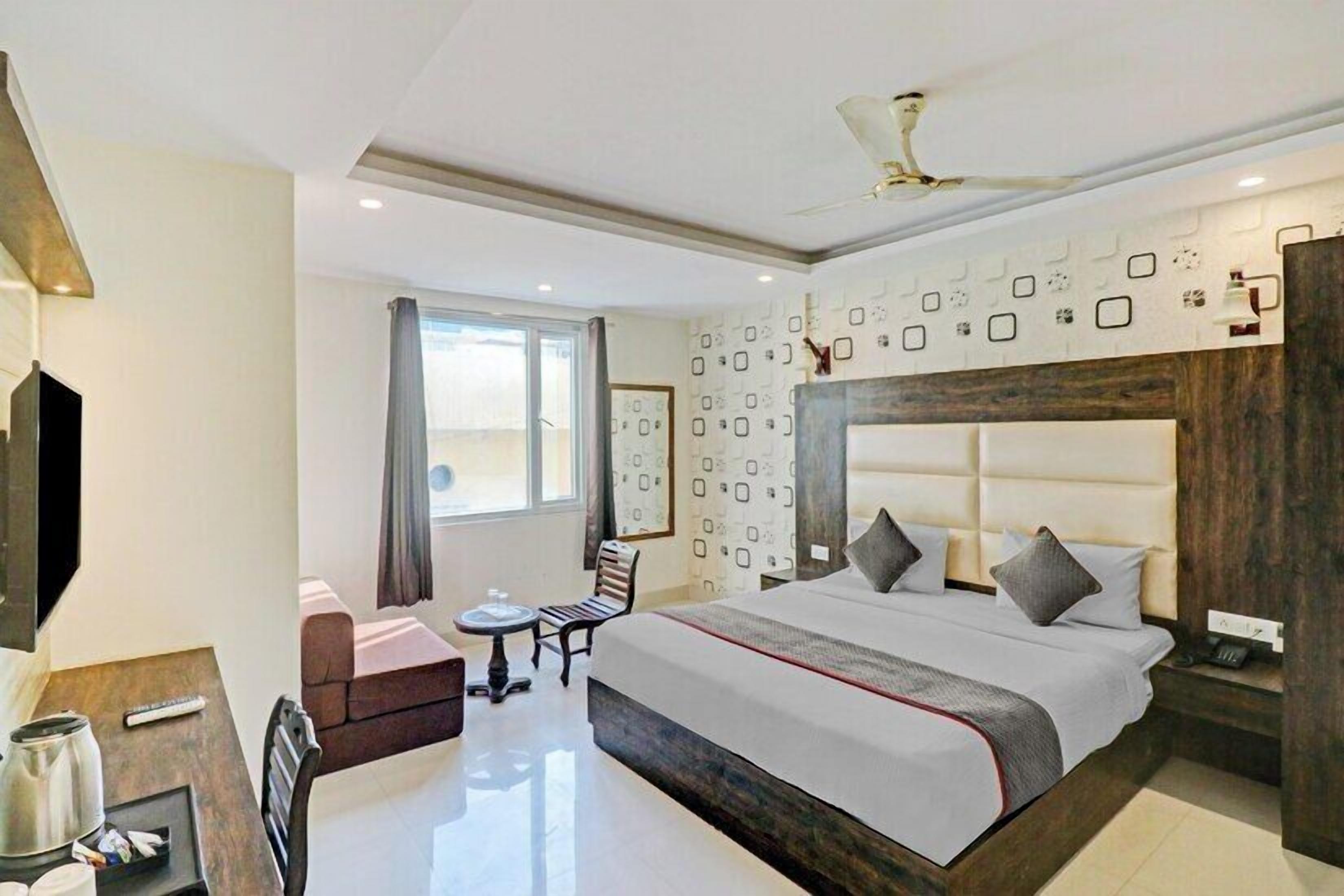 Quarto de hotel moderno com uma cama grande, uma escrivaninha, uma cadeira e uma televisão.
