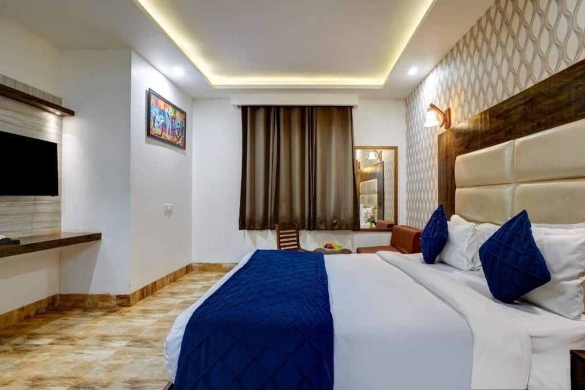 A hotel room with a bed, a TV, a desk, and a mirror.