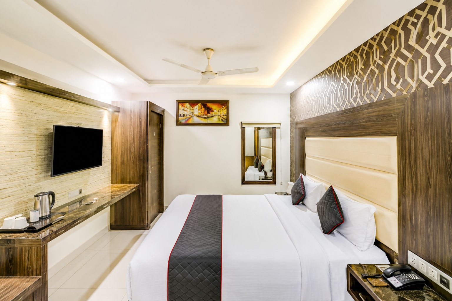 A hotel room with a bed, bedside table, TV, and a ceiling fan.