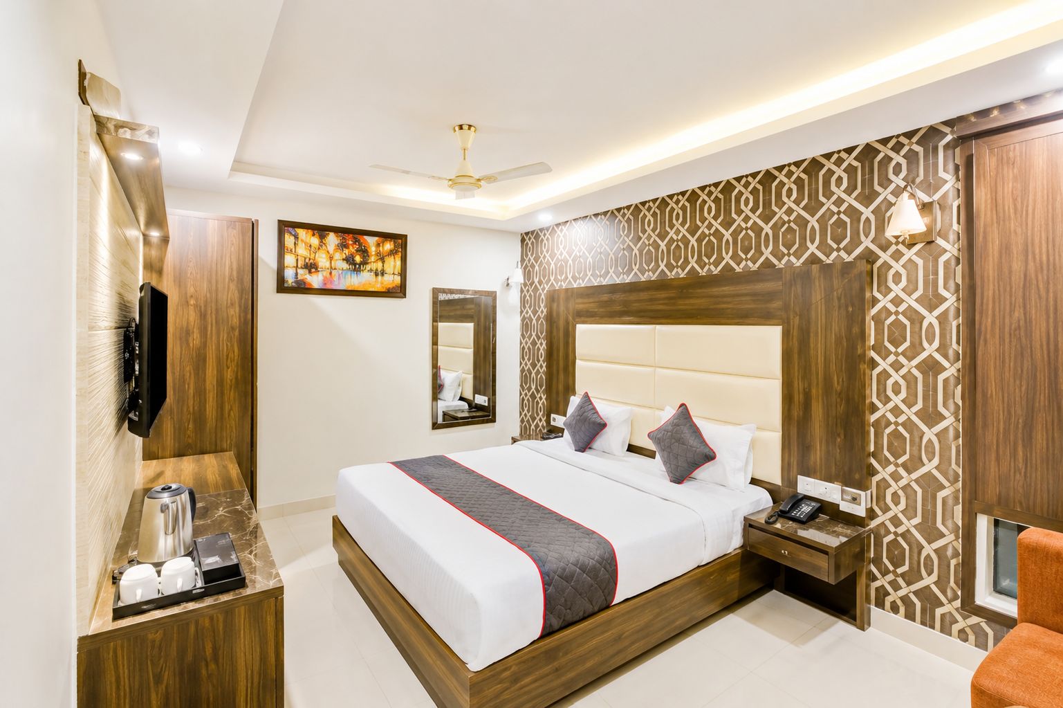 Habitación de hotel con una cama grande, mesitas de noche, televisor y cafetera.