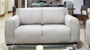A modern living room with a sofa, a glass coffee table, and a kitchen in the background. - On the Beach!  - walk to the mall and restaurants!  Great for remote workers (Manta)