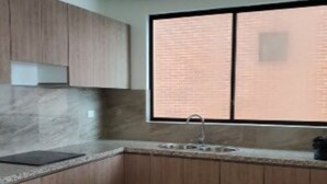A kitchen with wooden cabinets, a granite countertop, a sink, and a window with a view of a brick building. - On the Beach!  - walk to the mall and restaurants!  Great for remote workers (Manta)