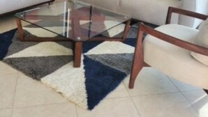 A living room with a beige sofa, a glass coffee table, and a patterned rug. - On the Beach!  - walk to the mall and restaurants!  Great for remote workers (Manta)