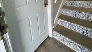 A staircase with a patterned design, a white door with 'APT A' sign, and a handrail.