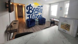 A living room with a large wall mural, a wooden dining table, blue armchairs, and a small side table.