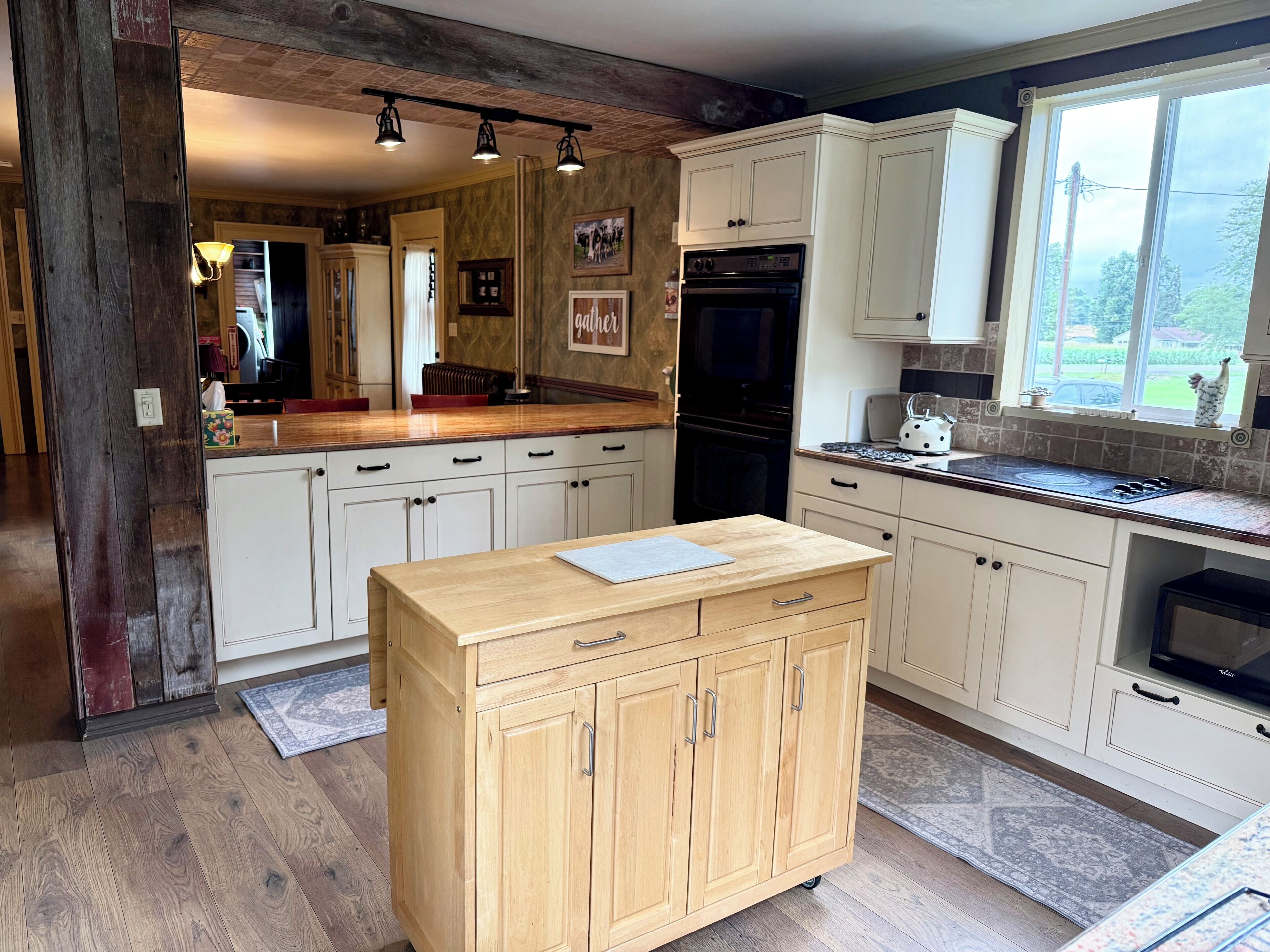 Une cuisine avec des meubles en bois, un îlot central et une fenêtre donnant sur un beau paysage.