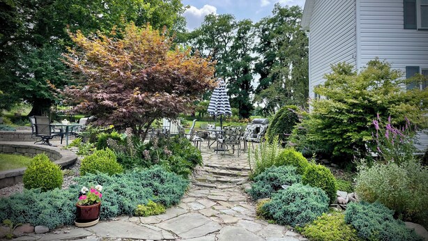 A stone pathway leading to outdoor seating with a tree and shrubs on either side. - Relax at The Farmhouse at Kindred Ground (Avon)