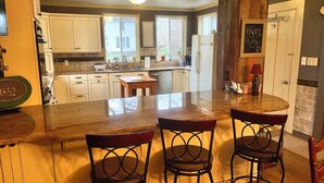 A kitchen with white cabinets, a granite countertop, and a dining area with two chairs. - Relax at The Farmhouse at Kindred Ground (Avon)
