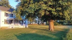 A two-story house with a porch and a large tree in front. - Relax at The Farmhouse at Kindred Ground (Avon)