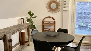 A dining area with a round table, black chairs, a wooden bench, a mirror, and a view of the outside. - Appartement Type Loft en Pleine Nature (Rumigny)