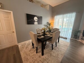 A dining area with a dark wooden table set for four, surrounded by upholstered chairs. A painting of a moon over water hangs on the wall. - No Cleaning Fee!
Luxury Villa Awaits! Close to Disney and New Attractions! (Davenport)