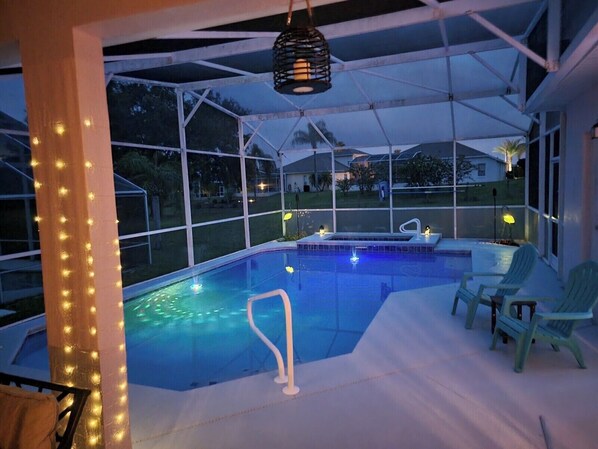 An indoor swimming pool with a clear view of the outside, surrounded by large windows and a covered area with chairs. - No Cleaning Fee!
Luxury Villa Awaits! Close to Disney and New Attractions! (Davenport)