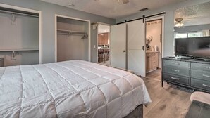 A bedroom with a large bed, a dresser, a ceiling fan, and a sliding door leading to a kitchen area. - ~ 9 Mi to Universal: Orlando Retreat w/ Sun Porch! (Orlando)