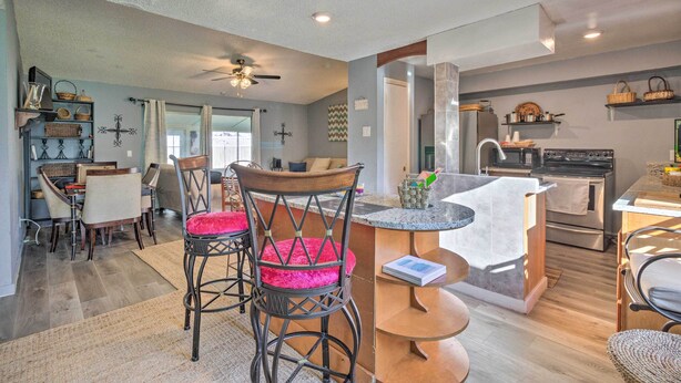 A modern kitchen with a central island, bar stools, and a dining area with chairs and a table. - ~ 9 Mi to Universal: Orlando Retreat w/ Sun Porch! (Orlando)