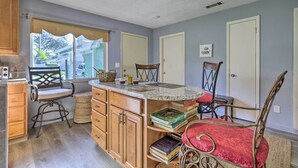 A kitchen with wooden cabinets, a marble countertop, and a dining area with chairs and a table. - ~ 9 Mi to Universal: Orlando Retreat w/ Sun Porch! (Orlando)
