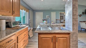 A kitchen with wooden cabinets, granite countertops, a built-in oven, and a stainless steel sink. - ~ 9 Mi to Universal: Orlando Retreat w/ Sun Porch! (Orlando)