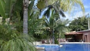 Una piscina circondata da palme e un edificio con balconi.