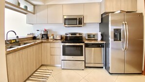 Una cucina moderna con elettrodomestici in acciaio inossidabile, tra cui frigorifero, forno, microonde e lavastoviglie.