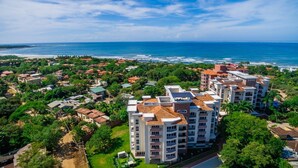 Una zona residenziale costiera con moderni palazzi a appartamenti, vista libera sull'oceano e vegetazione lussureggiante.