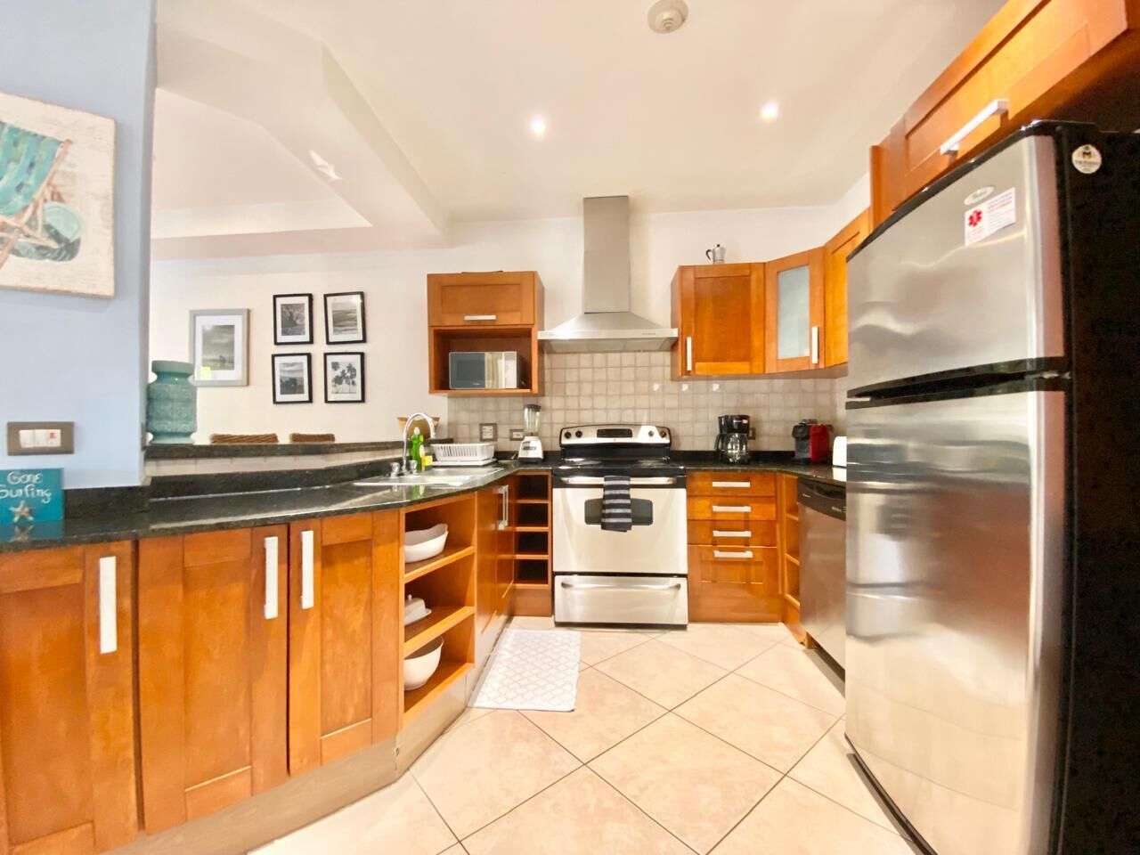 A modern kitchen with wooden cabinets, stainless steel appliances, and a tiled floor.