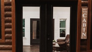 A cabin entrance with a wooden door, a welcome mat, and a sign reading "CABIN". - Stunning Farmhouse 1 mile to new casino sleeps 10 Hot Tub (Broken Bow)