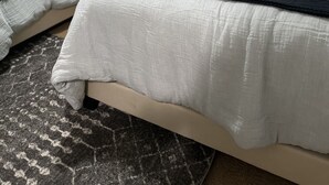 A bedroom with two beds, a nightstand, a lamp, and a patterned rug.