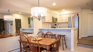 A modern kitchen with white cabinetry, a central island with stools, and a chandelier.