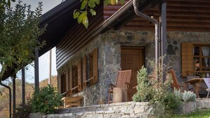 Ein rustikales Steinhaus mit einer Holzveranda, Steintreppen und Holzmöbeln.