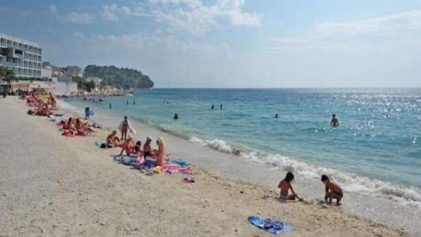 A beach with people sunbathing and swimming, a building on the left, and a clear sky. - Apartments Bay View - Studio with Balcony (Podstrana)