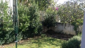 A grassy outdoor area with a metal fence, dense foliage, and a concrete wall. - Apartments Bay View - Studio with Balcony (Podstrana)