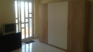 A room with a large wardrobe, a television on a stand, and a sliding glass door. - Apartments Bay View - Studio with Balcony (Podstrana)
