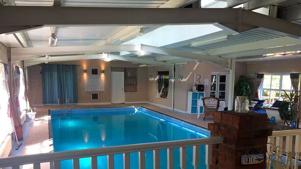 An indoor swimming pool with a white railing, a mosaic tile decoration, and a brick wall. - Log Cabin in Beautiful Countryside and Very Private (market rasen)