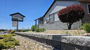 Un bâtiment de la chaîne Travel Inn, avec une façade en pierre, une grande enseigne et un arbre devant.