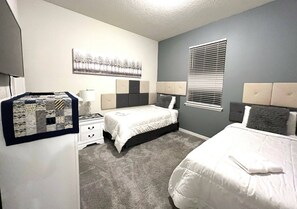 Une chambre avec deux lits, une table de chevet, une lampe et une œuvre d’art accrochée au mur.