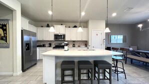A modern kitchen with a central island, stainless steel appliances, and pendant lighting.