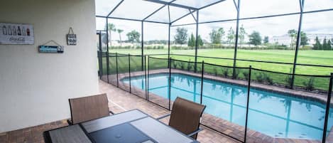 Un espacio exterior cubierto con una piscina, una mesa y sillas.