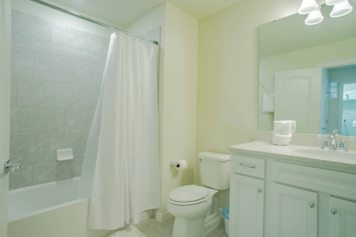 Een badkamer met douche, toilet en wastafel met spiegel.